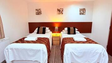 A hotel room with two beds, a central nightstand, and a radiator.