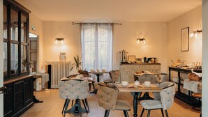 A cozy dining area with a table set for four, surrounded by upholstered chairs. A radiator and a potted plant are visible in the background. - Hôtel Le Chatellier – Piscine chauffée d’avril à octobre (Cancale)