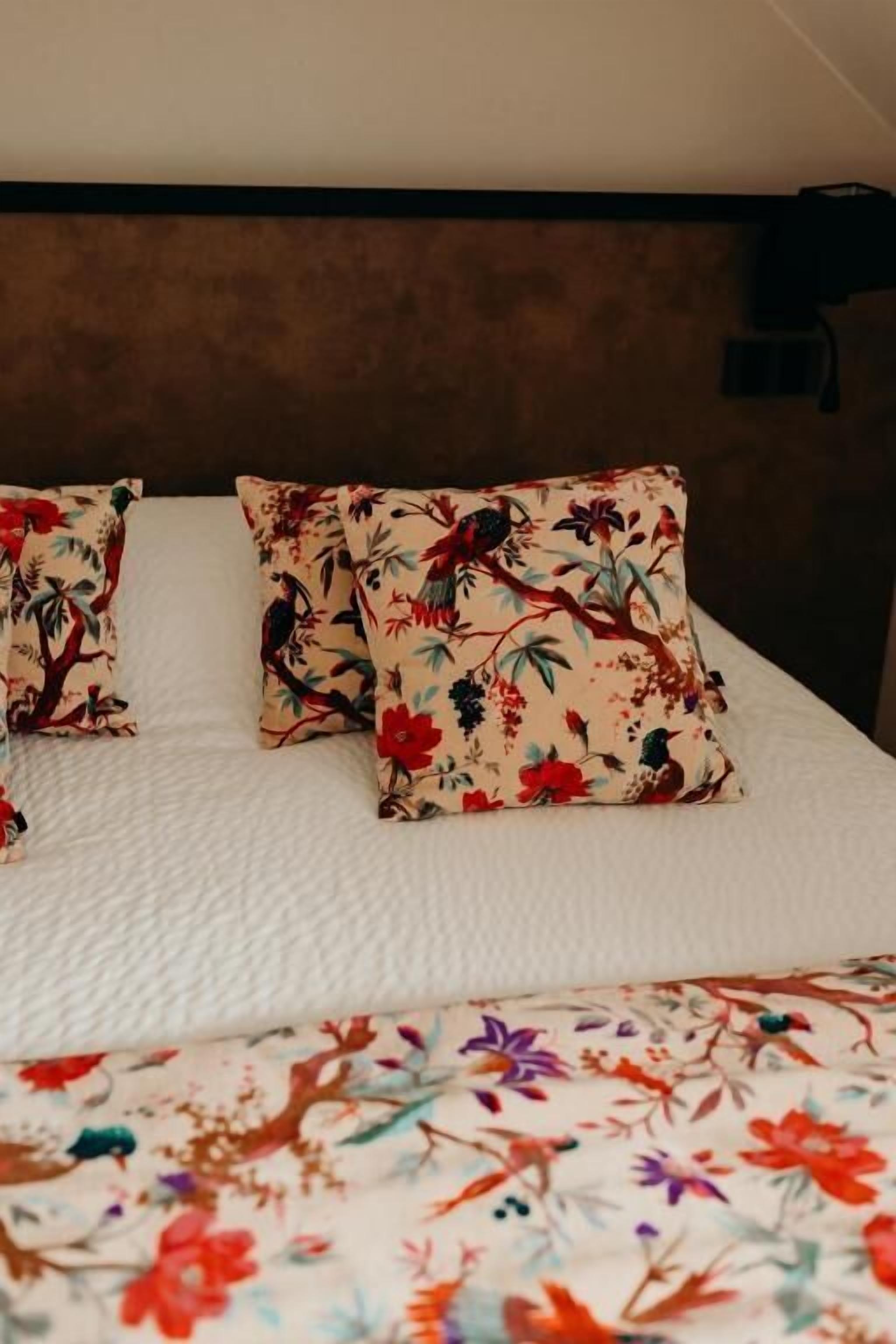 A bed with floral-patterned pillows and a matching bedspread.