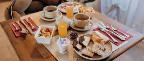 Una tavola imbandita con piatti di cibo, una brocca di succo d'arancia e una tazza di caffè.