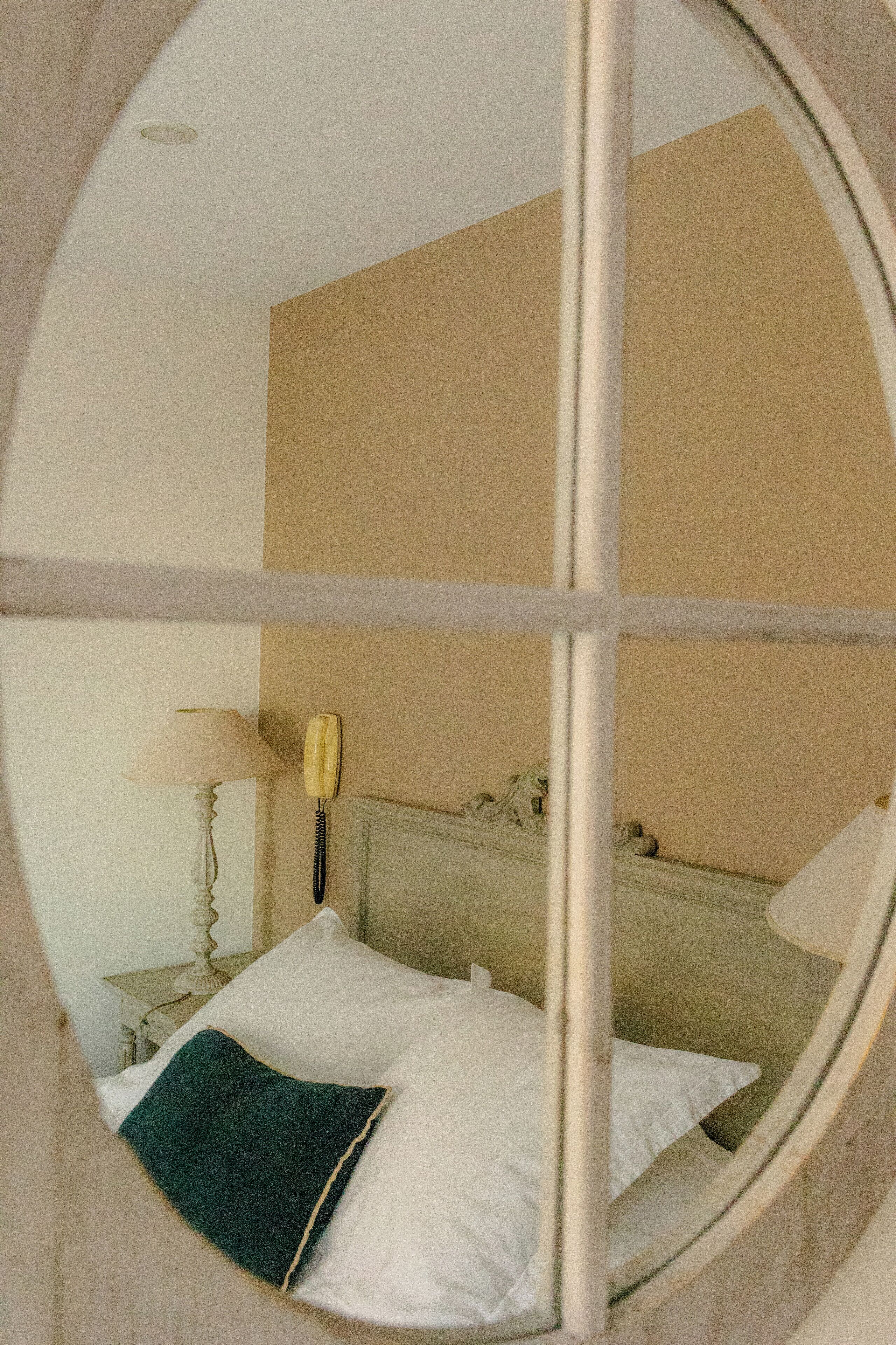 Um quarto com uma cama, mesa de cabeceira, abajur e telefone.