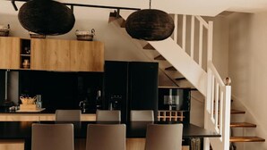 A modern kitchen with a central island, wooden cabinets, and a staircase leading to an upper level. - Hôtel Le Chatellier – Piscine chauffée d’avril à octobre (Cancale)