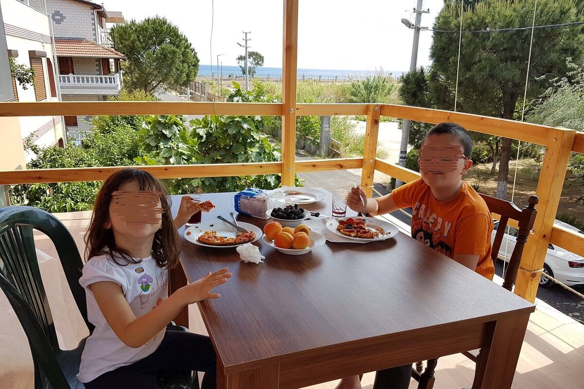 A wooden table with plates of food, a glass of water, and a box of tissues.