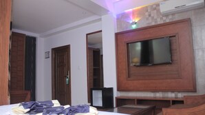 A hotel room with a bed, a TV mounted on the wall, a wooden cabinet, and a small table. - Zimbo Golden Hotel (Dar es Salaam)