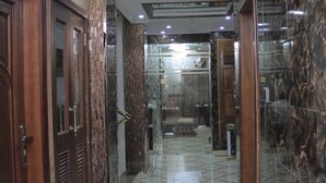A hallway with patterned flooring, wooden doors, and a glass elevator. - Zimbo Golden Hotel (Dar es Salaam)