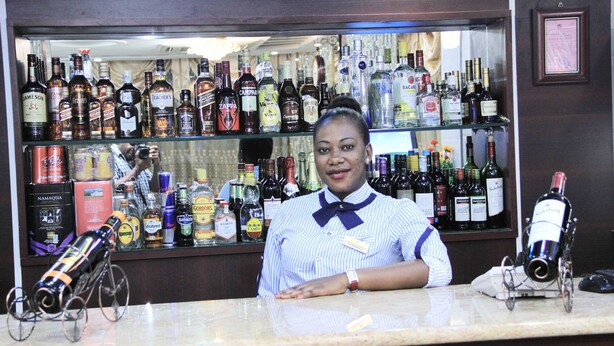 A bar with a variety of liquor bottles and a bartender. - Zimbo Golden Hotel (Dar es Salaam)