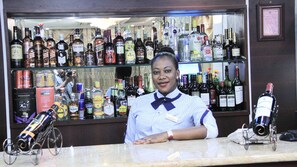 A bar with a variety of liquor bottles and a bartender. - Zimbo Golden Hotel (Dar es Salaam)
