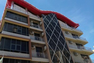 A multi-story building with balconies, air conditioning units, and a distinctive red awning.