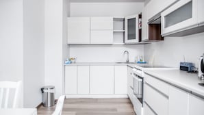Eine moderne Küche mit weißen Schränken, einer Edelstahl-Spüle und einem eingebauten Backofen.