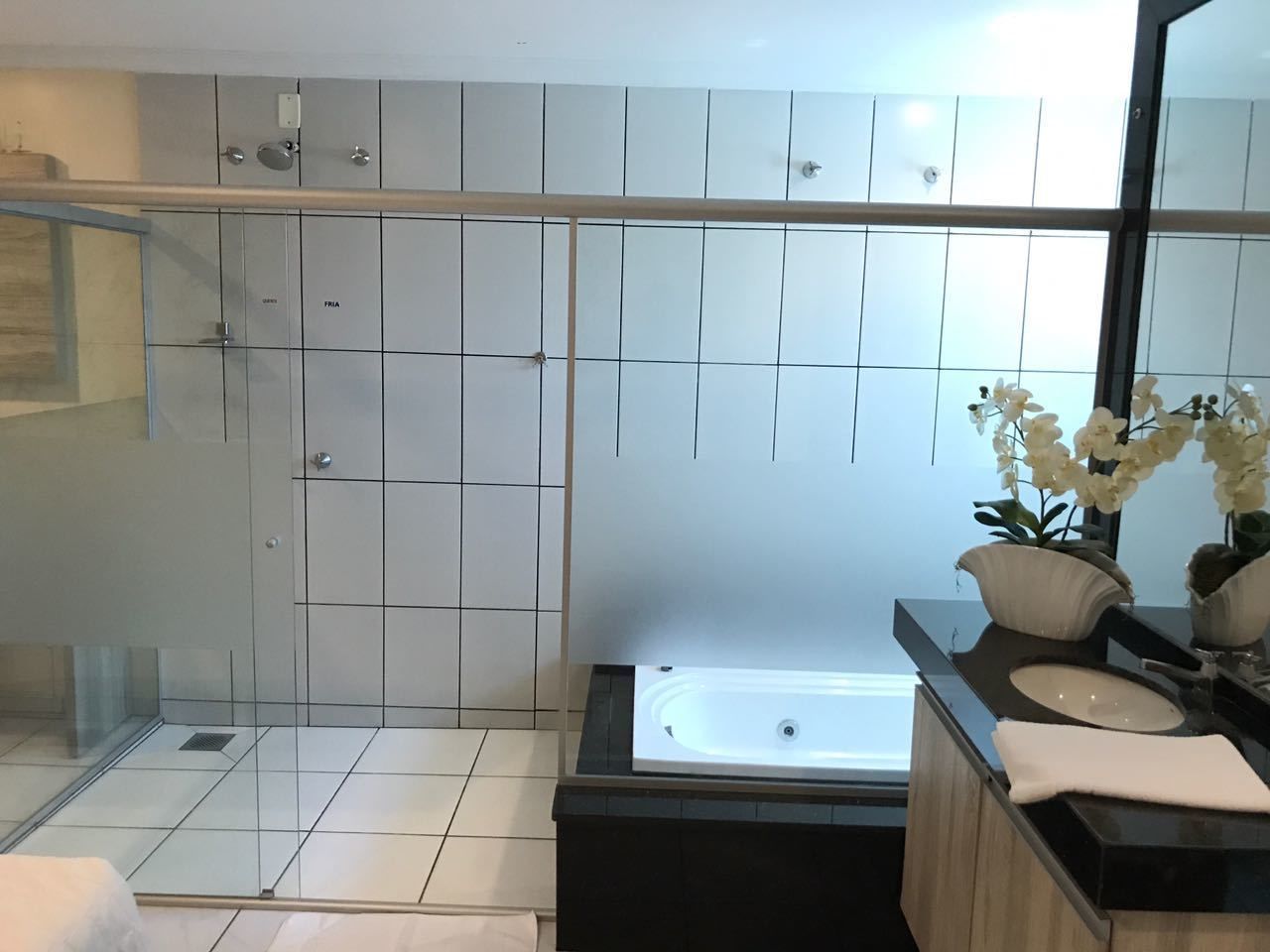 Casa de banho moderna com chuveiro em cabine de vidro, banheira independente e toucador com lavatório e espelho.