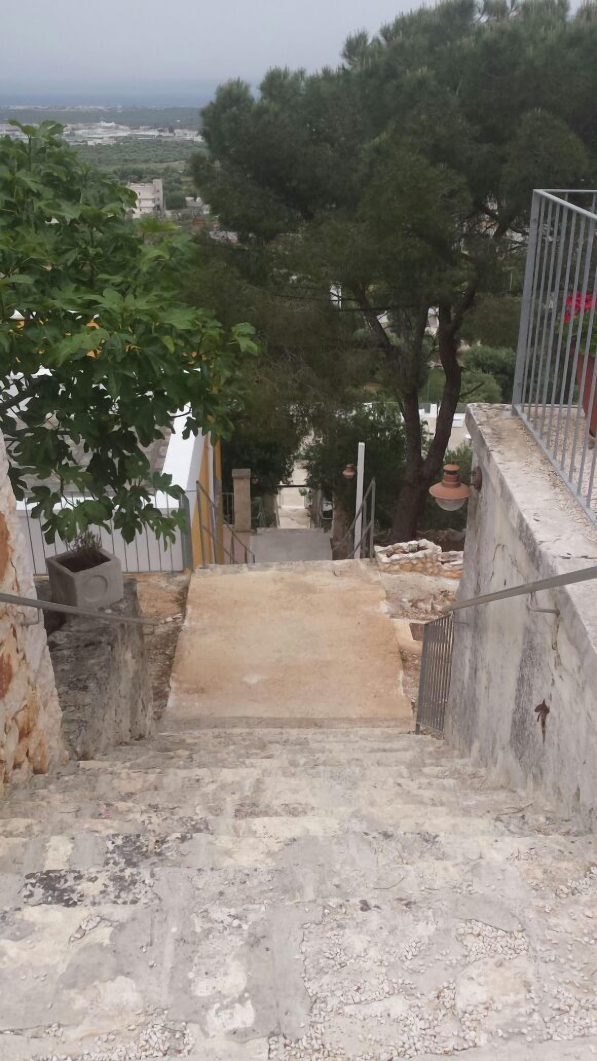 Un escalier menant à un bâtiment d’où l’on peut admirer la vue sur la ville au loin.