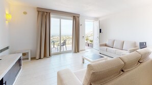 Una sala de estar moderna con un sofá, una mesa de centro y vistas a la ciudad a través de amplias ventanas.