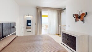 Una habitación de hotel moderna con una cama grande, un armario, una obra de arte de una mariposa en la pared y vistas al exterior.