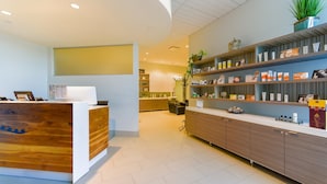 A reception area with a wooden reception desk, a counter with shelves displaying products, and a potted plant. - Tioga Downs Casino and Resort (Nichols)
