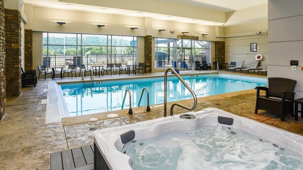 An indoor swimming pool with a hot tub, lounge chairs, and a view of the outdoors. - Tioga Downs Casino and Resort (Nichols)
