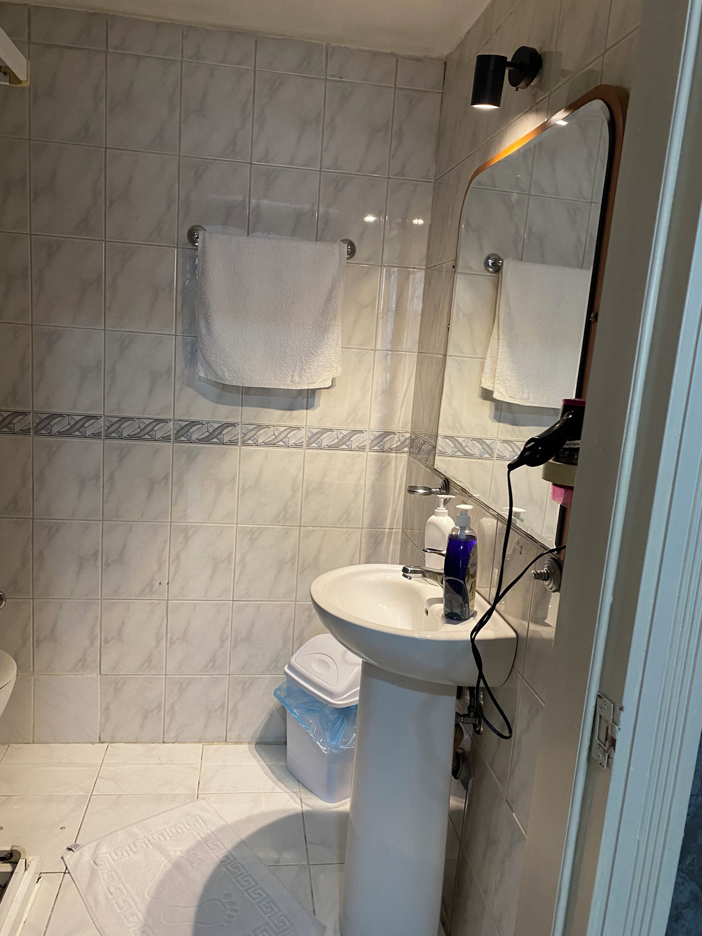 A bathroom with a white sink, a mirror, and a towel hanging on the wall.