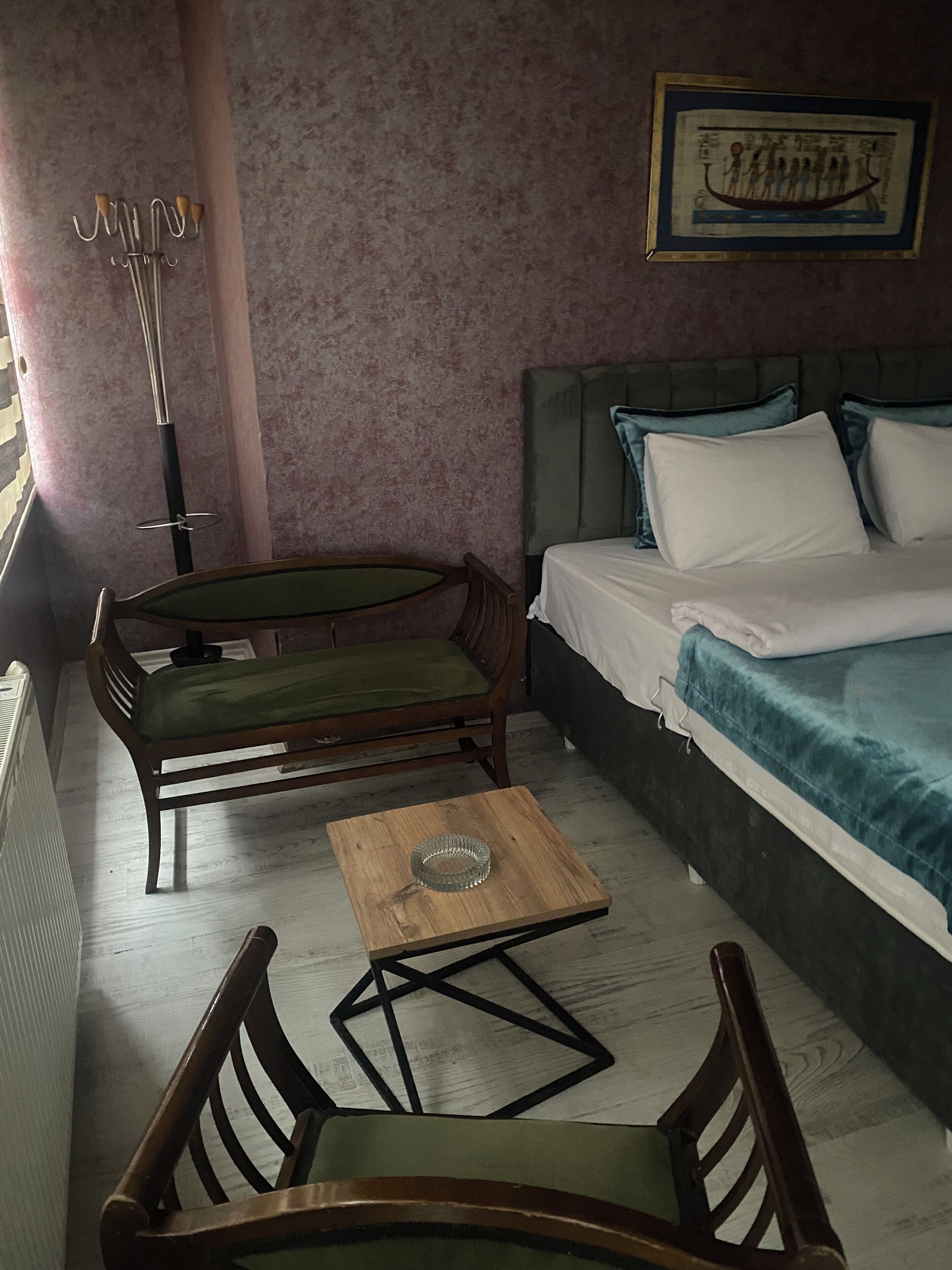 Una habitación con una cama, una silla, una mesita y un radiador.