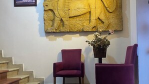 A reception area with a stone relief, two purple chairs, a potted plant, and a staircase. - Masal Otel (Izmit)