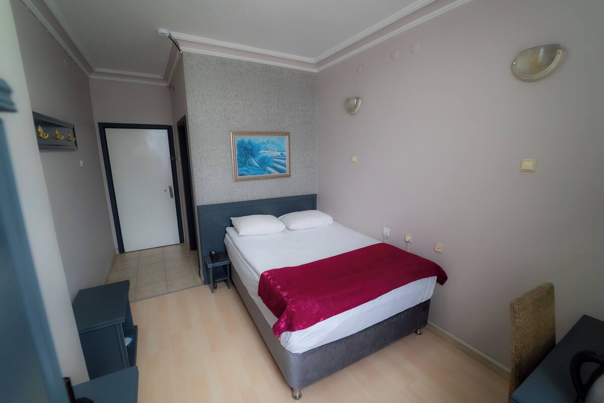 Ein Schlafzimmer mit einem Bett, einem Nachttisch, einer Tür, einem Gemälde und einer Lampe.