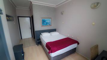 Una camera da letto con un letto, un comodino, una porta, un quadro e un lampadario.