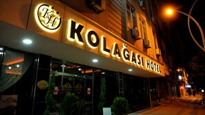 Kolagası Hotel set fra ydersiden, med oplyst skiltning, glasdøre og en lygtepæl i nærheden.