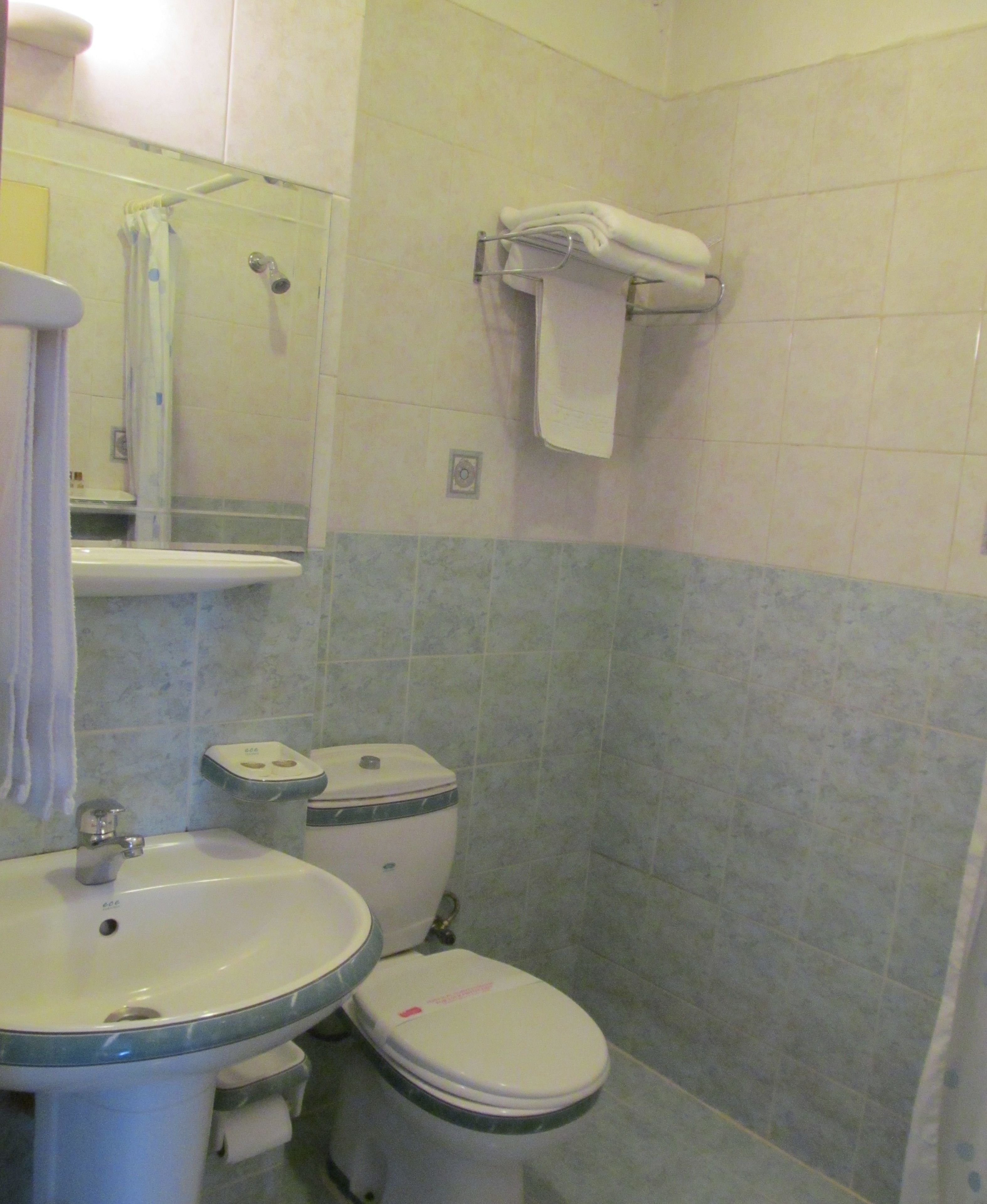 Casa de banho com lavatório, sanita e porta-toalhas.