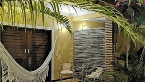 Un hamac, deux chaises, un mur de briques et un palmier dans un espace intérieur bien éclairé.