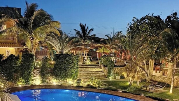 Une piscine entourée d’une végétation luxuriante et une terrasse bien éclairée.