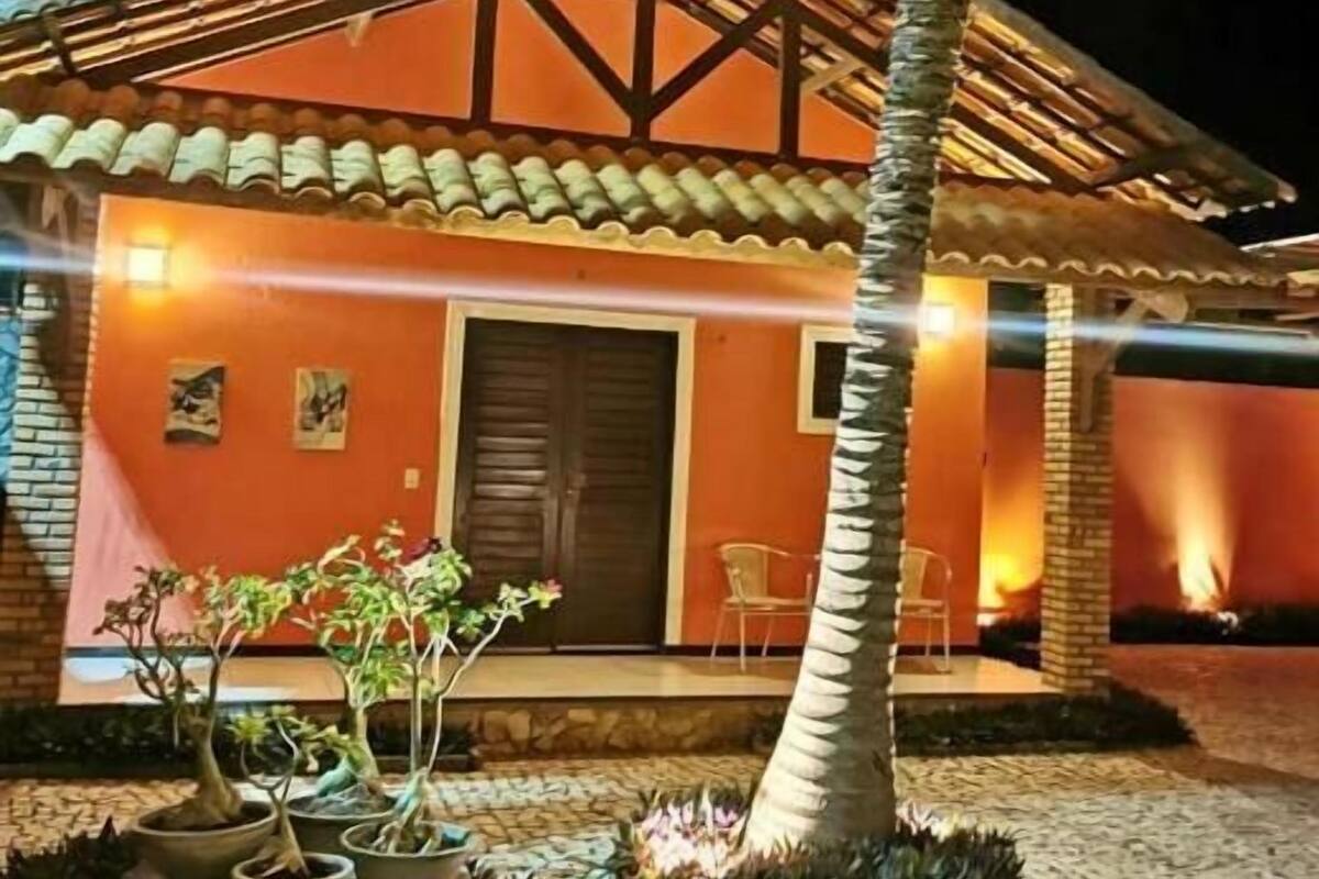 A building with a tiled roof, a palm tree, and potted plants in the foreground.