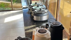 Un plan de travail de cuisine avec une machine à café, un distributeur d’eau et une bouilloire.