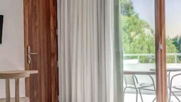 Ein modernes Zimmer mit einem runden schwarzen Tisch, einer Couch, einer Holztür und einem großen Schiebeglasfenster, das zu einem Außenbereich mit Stühlen führt.