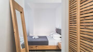 A small, neatly arranged bedroom with a single bed, a wooden headboard, and a stone floor.