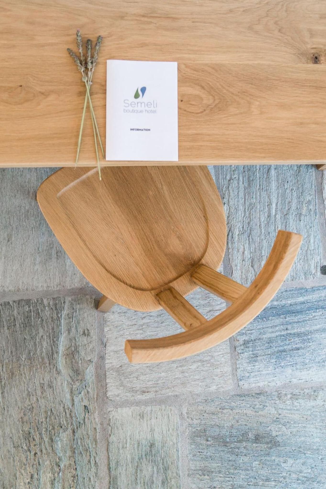 A wooden table with a white card labeled "Semeli boutique hotel" and a small bunch of dried lavender.
