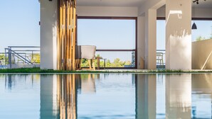 Ein moderner Poolbereich mit klarem Wasser, einer Holzterrasse und Blick zum Himmel.
