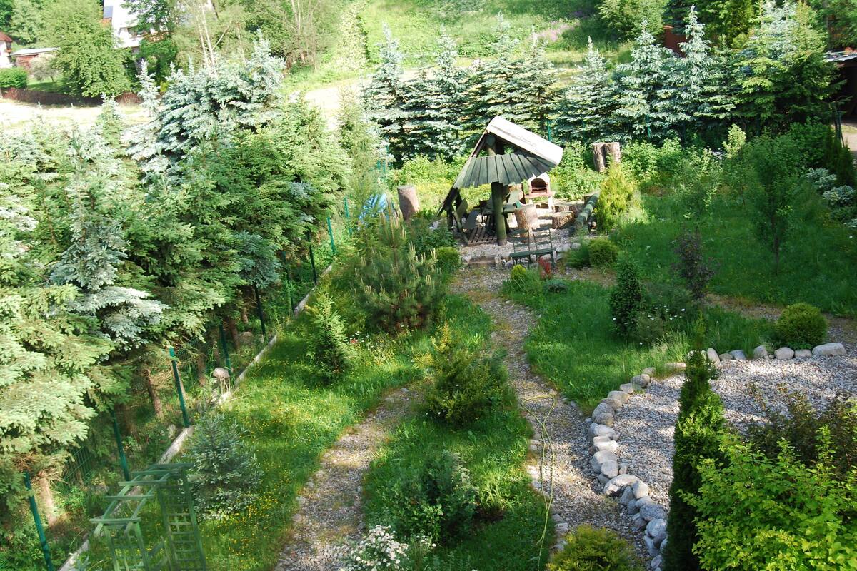 A garden with a gazebo, a gravel path, and various trees.