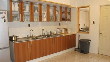 A kitchen with wooden cabinets, a sink, and a trash bin.