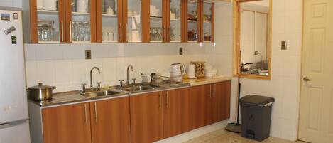 A kitchen with wooden cabinets, a sink, and a trash bin.