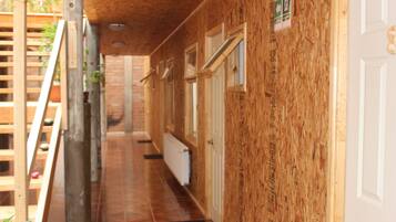A wooden interior hallway with a tiled floor, a radiator, and a door with a window.