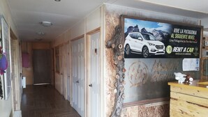 A hallway with wooden flooring, white doors, and a wall-mounted sign advertising a car rental service.