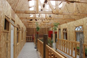 Een houten constructie binnen met een hoge plafond, houten leuningen en meerdere ramen.