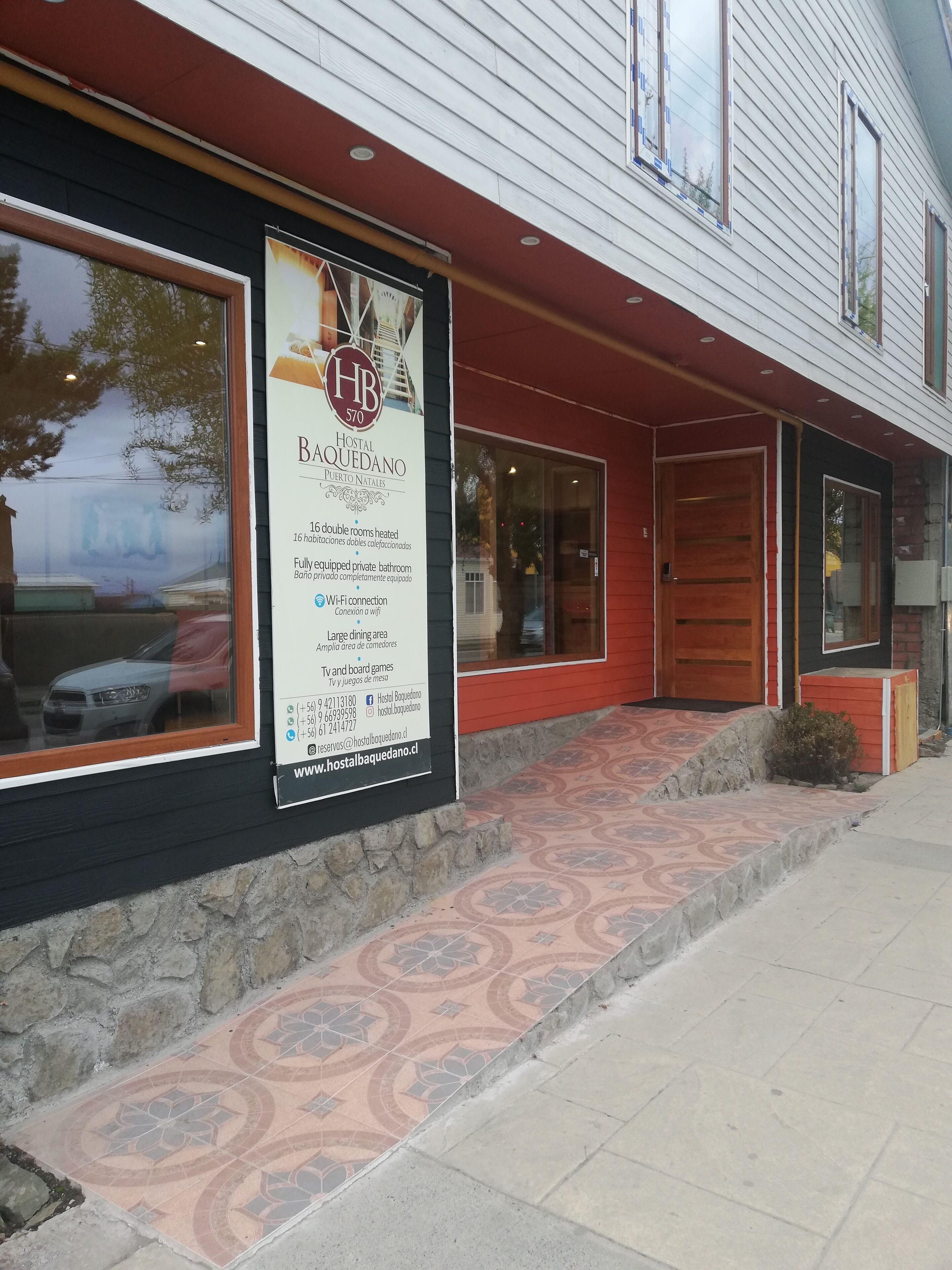 A hotel exterior with a large sign advertising 16 double rooms, Wi-Fi, and a large dining area.