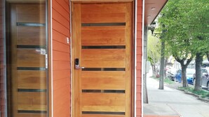 A wooden door with horizontal slats, a black mat at the entrance, and a patterned tile floor.
