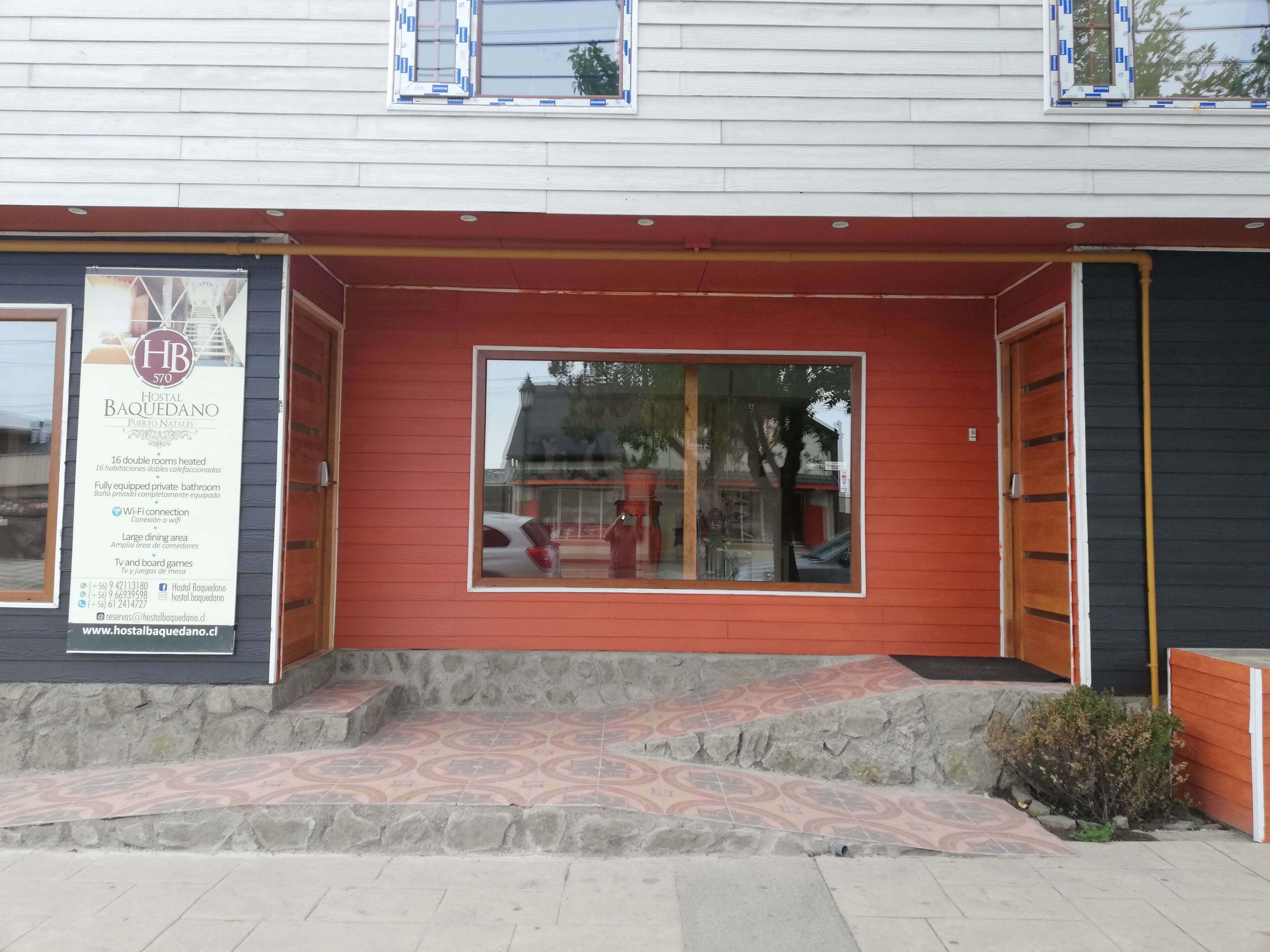 A hotel entrance with a red facade, a large window, and a stone-paved entrance.