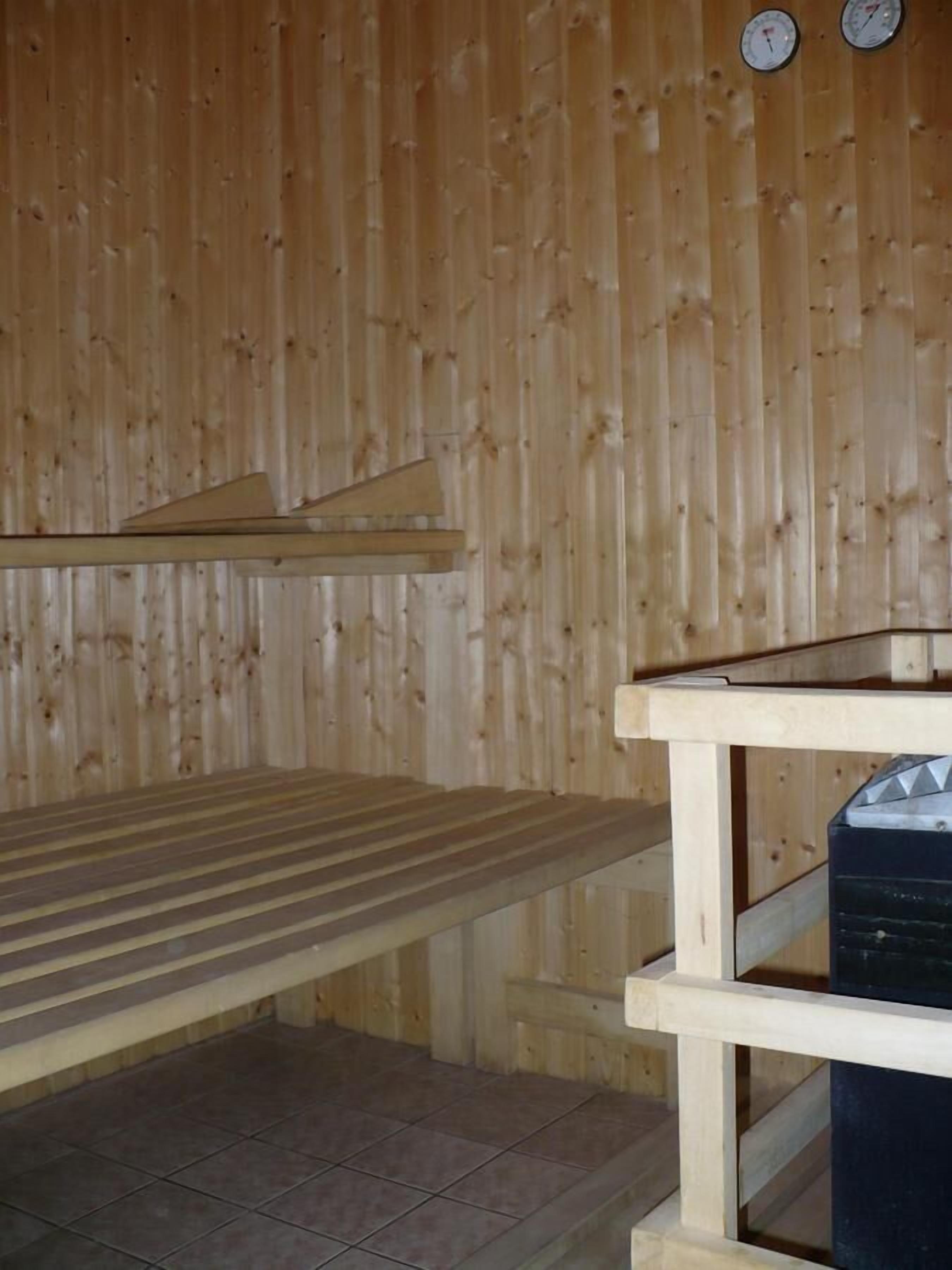 Una habitación de madera con un banco, una mesa y un termostato en la pared.