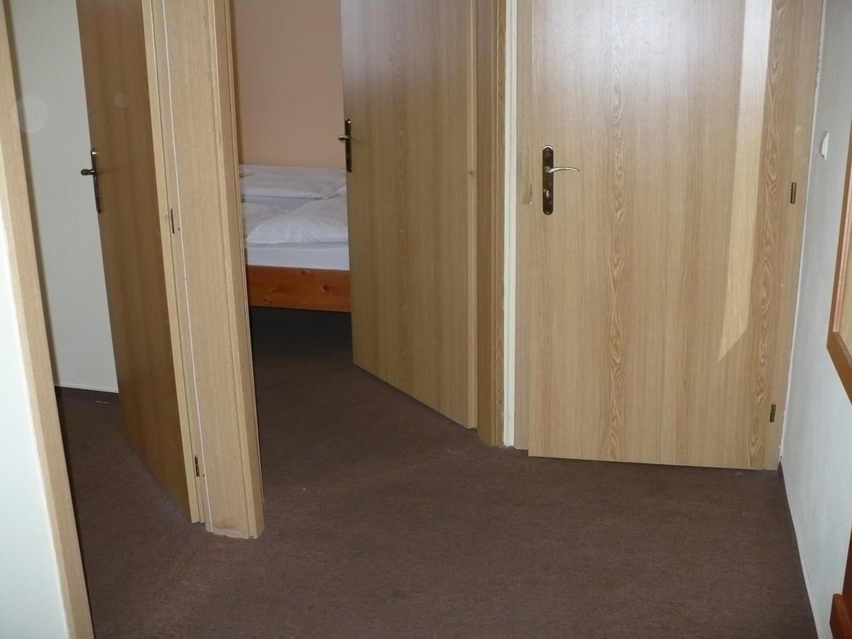 Un pasillo estrecho con puertas de madera que dan a un dormitorio con cama.