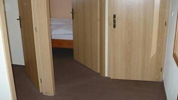 Un pasillo estrecho con puertas de madera que dan a un dormitorio con cama.