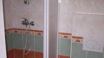 Un baño con ducha, inodoro y un lavamanos pequeño.