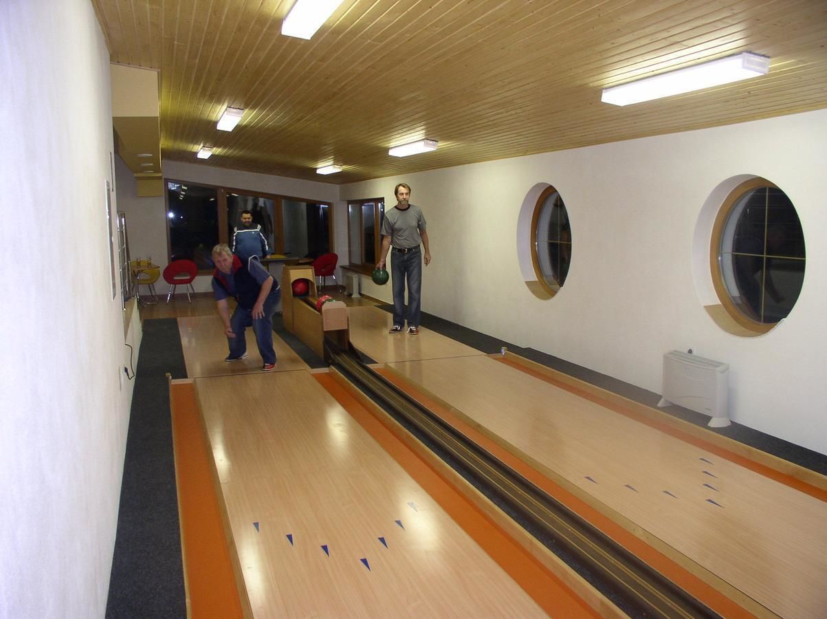 Een bowlingbaan met houten banen, een persoon aan het einde en enkele mensen die bowlen.
