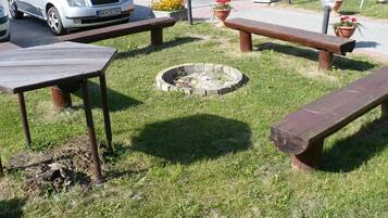 Zona verde con mesas de picnic y un pozo para fogatas.