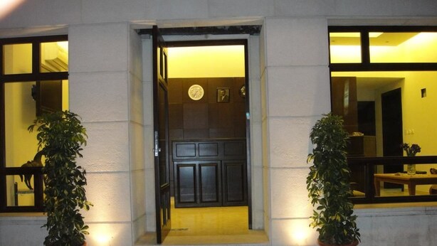 A building entrance with a door, steps, and two potted plants. - Madaba Hotel (Madaba)